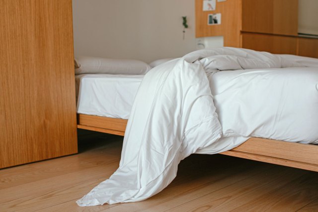 An unmade bed with white bedding