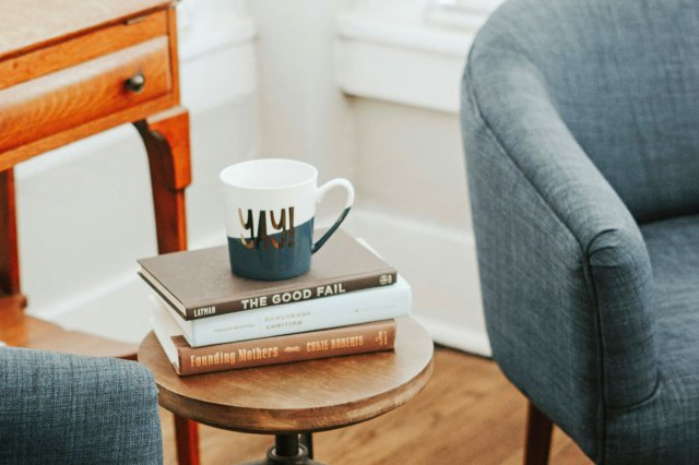 A coffee mug set on top of a stack of books and journals