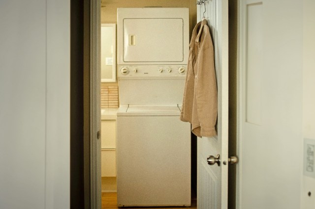 A washer and dryer with a shirt hanging on a hanger over the door