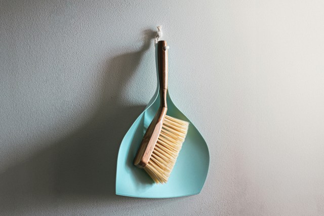 A dust pan and brush hanging on a wall