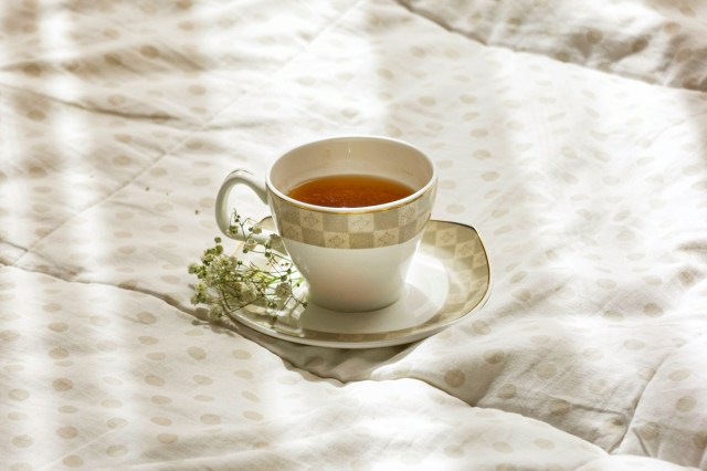 A mug of tea resting on a bed