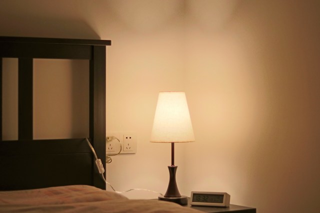 A bedside lamp on next to a bed