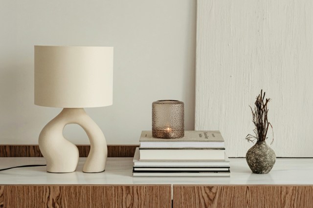 A dresser with decor and a lamp on top 