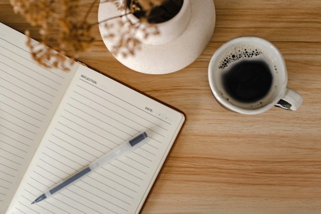 An open journal next to a cup of coffee