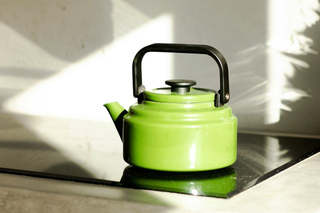 A green teapot on a stovetop