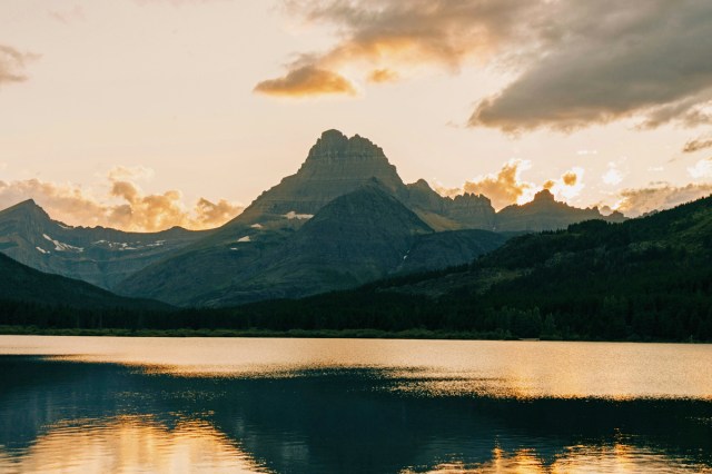 The sun setting behind an alpine lake