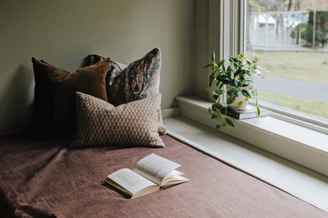 A book left open on a bed next to a window