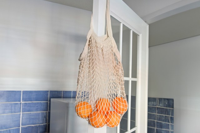 A bag of oranges hanging on a door