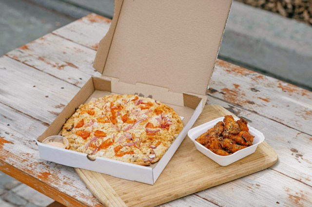 A pizza and chicken wings in takeout boxes