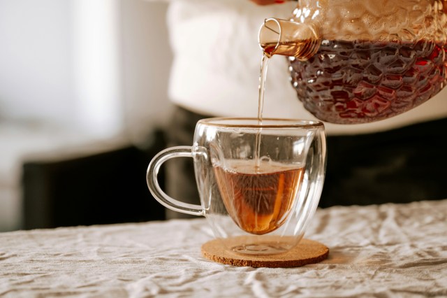 A pot of tea being poured into a mug